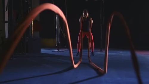 Strong Woman Doing Battle Rope Exercise at Gym