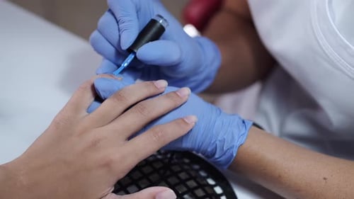 Close-up of Beautician Hands Making Blue Manicure for Client