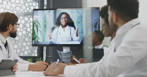 El equipo médico celebra una videoconferencia en línea con su colega en una pantalla interactiva