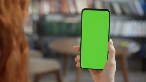 Back View of Young Woman at Home Office Sitting on Library Collage With Green Mockup Screen