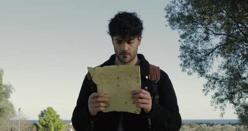 Man Holds Document Outside on a Sunny Day