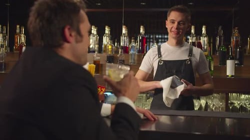 Bartender Cleans Glass While Talking to Customer