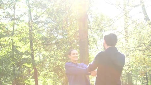 Slow motion shot of couple holding hands and spinning around in woods