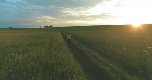 Sporty Child Runs Through a Green Wheat Field in Summer Rain