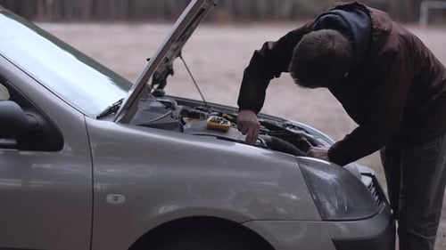 Man Repairing Car Engine in Rural Setting