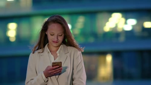 Woman Using Phone in City at Night