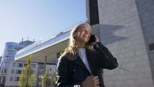 Beautiful Young Woman is Walking on the City Street while Talking with Her Friend