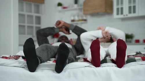 Couple Relaxing on Bed Wearing Matching Pajamas