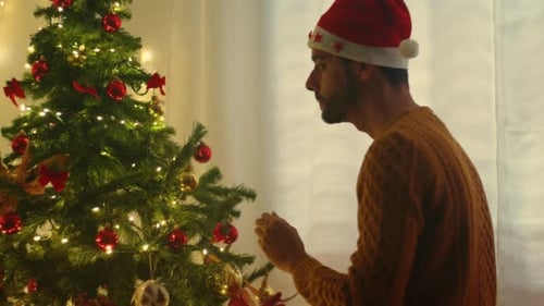 Young Man Decorating Christmas Tree at Home