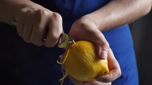 Peeling a bright yellow lemon with a tool