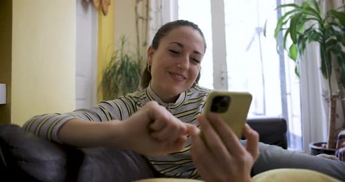 Woman Using Smartphone and Smiling on Couch at Home
