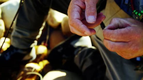 Fly fisherman preparing string to tie on hook