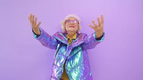 Contented, Fun-loving Older Woman Enjoys Her Charm By Posing for the Camera Against an Isolated