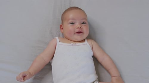 Happy Infant Smiling and Waving Arms on Bed