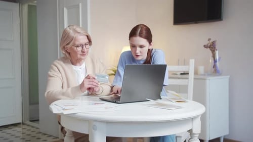 Senior Woman and Young Adult Using Laptop at Home