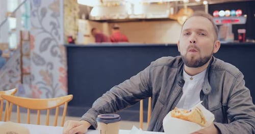 Man Enjoying a Burger in a Fast Food Cafe
