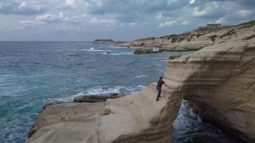 A Girl Climbs a Rock on the Sea Coast