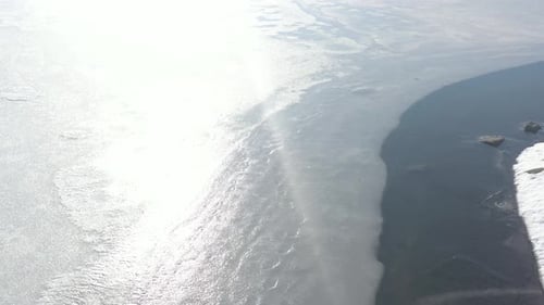 Ice and snow on coastal area of lake by winter 4K aerail video