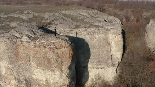 Woman taking pictures on her smart phone while standing at the edge of stunning rock formation