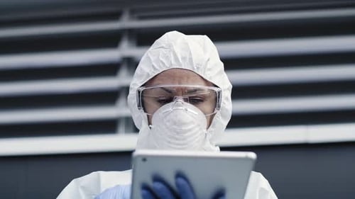 Person in Protective Suit Using Tablet Indoors