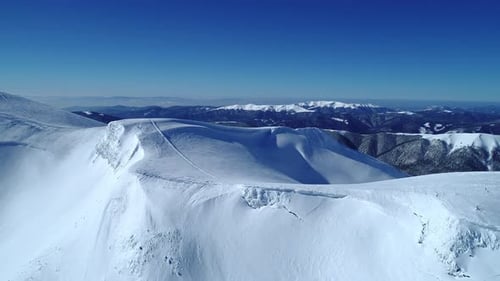 Survol des montagnes enneigées et turquoises illuminées par le soleil du jour
