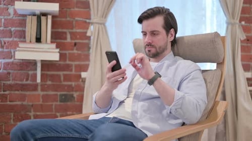 Relaxed Man Using Mobile Phone in Modern Home