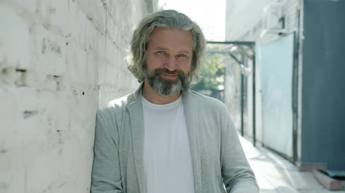 Smiling Man Leaning Against White Brick Wall