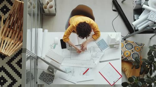 Top Down of Female Architect Drawing Floor Plan at Office Desk