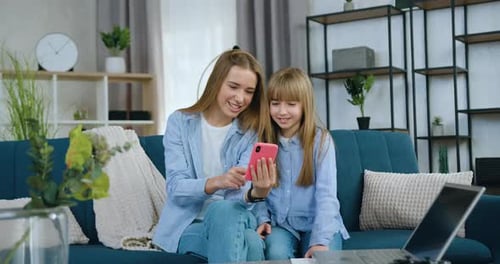 Des sœurs s'amusent ensemble tout en passant des loisirs communs à la maison à regarder des vidéos amusantes