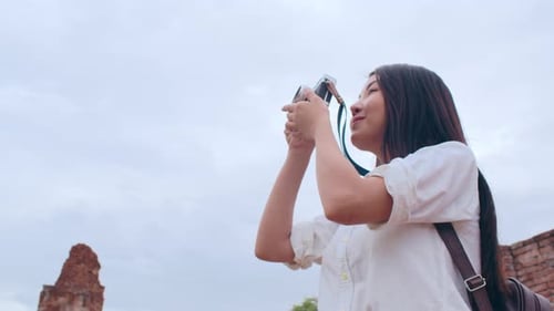 Asian woman using camera for take a picture while spending holiday trip at Ayutthaya, Thailand.