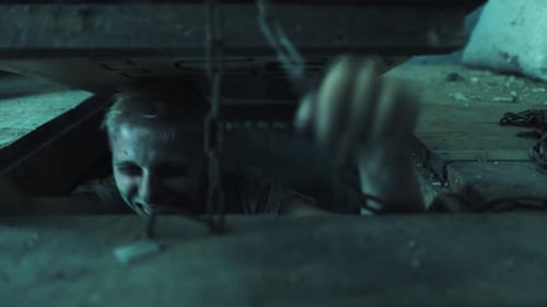 Stressed Man Exiting Chained Hatch in Dark Room