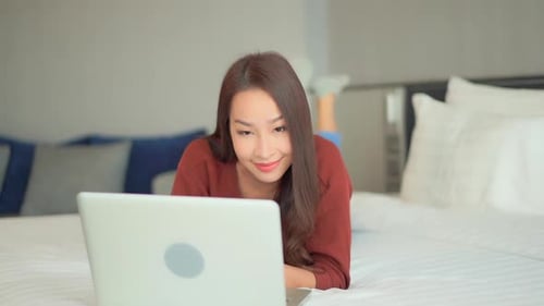 Excited Woman Using Laptop While Lying on Bed