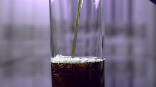Dunkles Soda wird aus einer Plastikflasche in ein Glas gegossen, Nahaufnahme, Bewegung nach oben