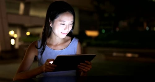 Woman Using Tablet Device at Night