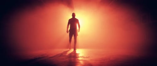 Silhouette of Muscular Man Walking Through Smoke