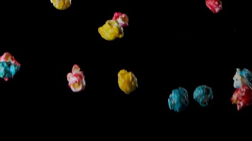 Mehrfarbiges Popcorn fliegt isoliert auf schwarzem Hintergrund