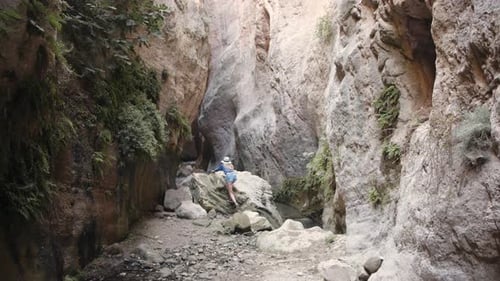 Touristin im Hut klettert über Steine im Canyon
