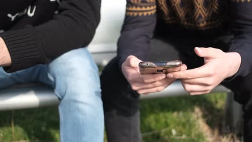 Young Adults Share Cell Phone Content Outdoors