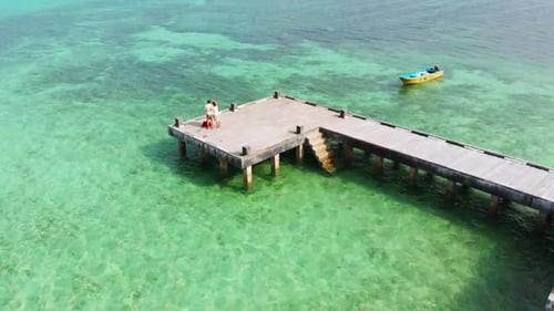 Couple on vacation looking at view on pier caribbean sea tropical coral reef in
