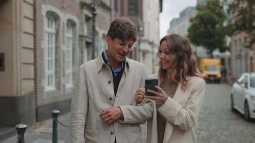 Mature Couple Walking on Street and Using Smartphone