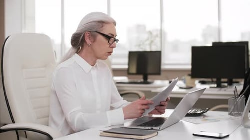 Grey-haired Business Lady Working on Laptop in Office on Weekend