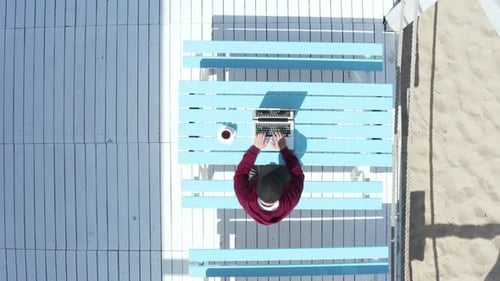 Freelancer masculino trabalhando em um laptop enquanto está sentado em um café de férias