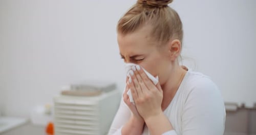 Woman with Tissue Blowing Her Nose Indoors