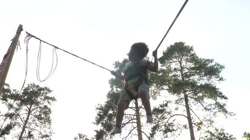 Little Child Jump on theTrampoline with Elastic Ropes. Happy Boy Is Flying Up To the Sky. Baby