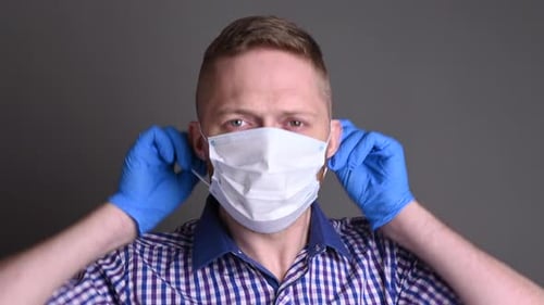 Adult Puts on Medical Mask and Blue Gloves