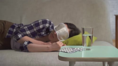Une jeune femme portant un masque de sommeil se retourne et se retourne dans son sommeil ne peut pas dormir au premier plan de l'insomnie