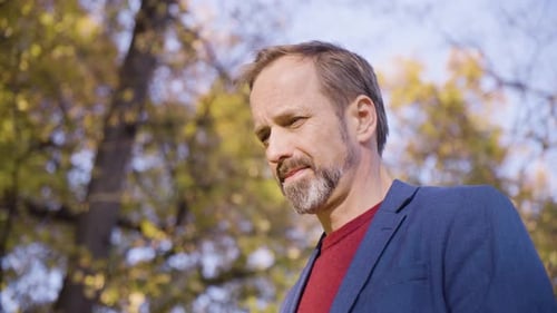 A Middleaged Handsome Caucasian Man Looks Around in a Park in Fall Closeup From Below