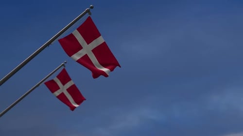 Two Danish Flags Waving Against a Clear Blue Sky