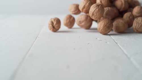 Pouring Walnuts onto a White Wooden Surface