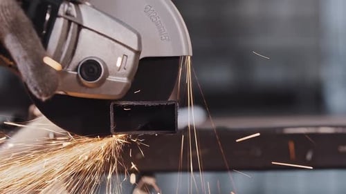 Manufacturing Plant Worker Cutting the Part of Metal Detail with Angle Saw Bright Sparkles